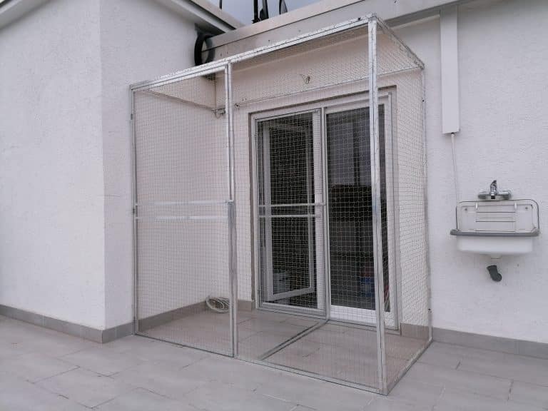 Katzengitter mit Tür aus Metall an der Hauswand